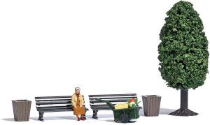 Frau mit Handwagen und Ladung. Parkbänke und Abfallkörbe
